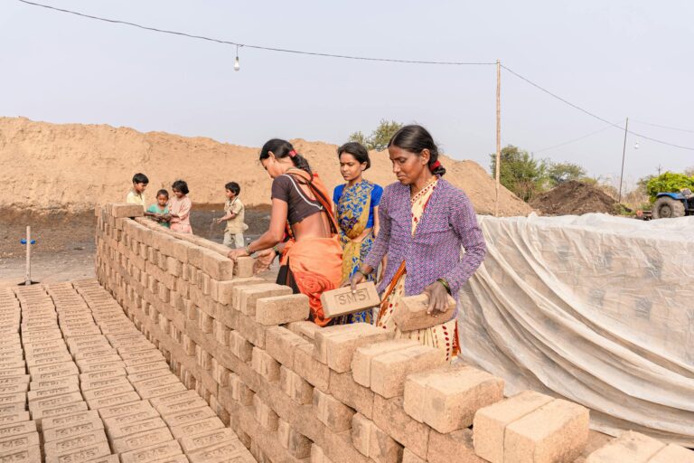Women constructing a brick wall outdoors, symbolizing teamwork in rural settings.